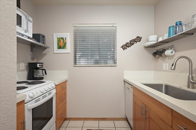 kitchen featuring light tile patterned floors, white appliances, and sink