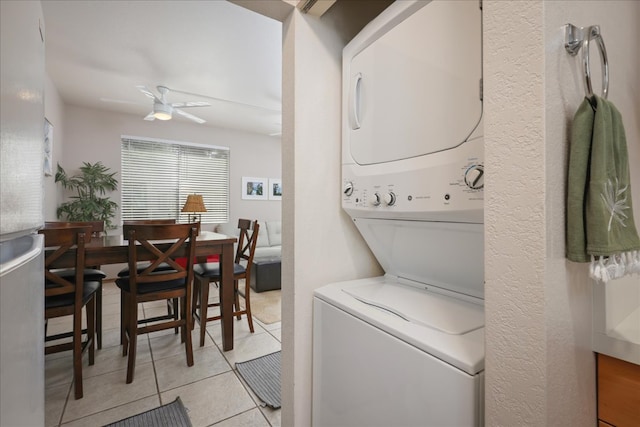 clothes washing area featuring light tile patterned flooring, ceiling fan, and stacked washer and dryer