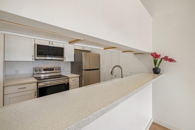 kitchen featuring sink, white cabinetry, stainless steel appliances, and light hardwood / wood-style flooring