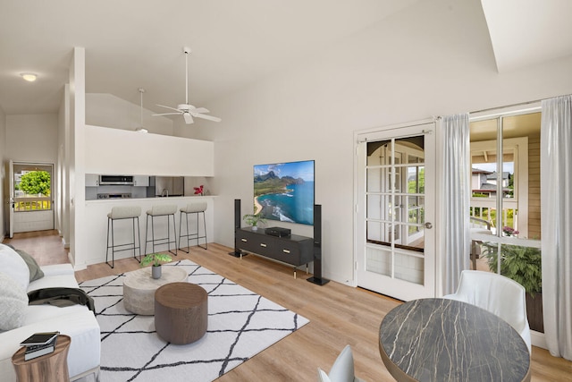 living room with high vaulted ceiling, light hardwood / wood-style flooring, and ceiling fan