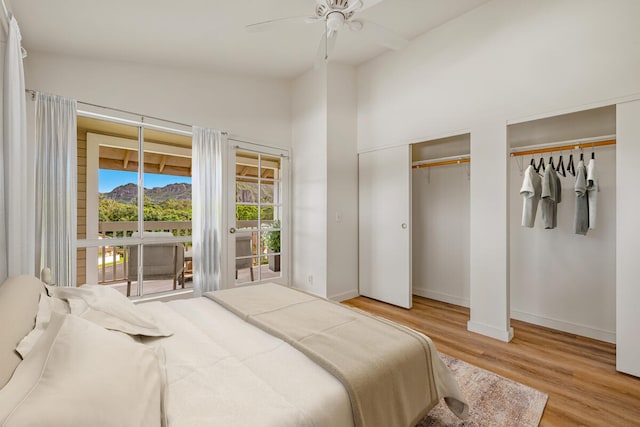 bedroom with two closets, ceiling fan, light hardwood / wood-style floors, and vaulted ceiling