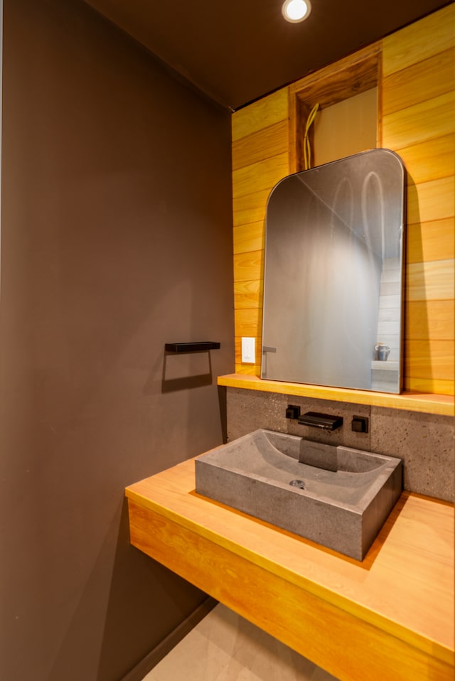 bathroom featuring wooden walls and sink