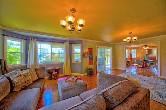 living room with ornamental molding, a textured ceiling, light wood-type flooring, and ceiling fan with notable chandelier