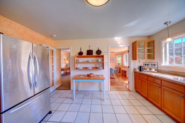 kitchen featuring stainless steel refrigerator, light tile patterned floors, and pendant lighting