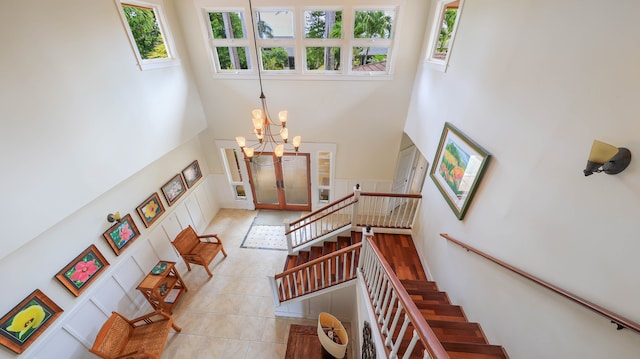 tiled entryway with a wealth of natural light, a towering ceiling, and a chandelier