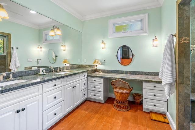 bathroom with crown molding, vanity, hardwood / wood-style flooring, and a tile shower