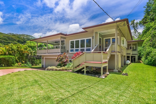 rear view of house featuring a yard, a garage, and a deck