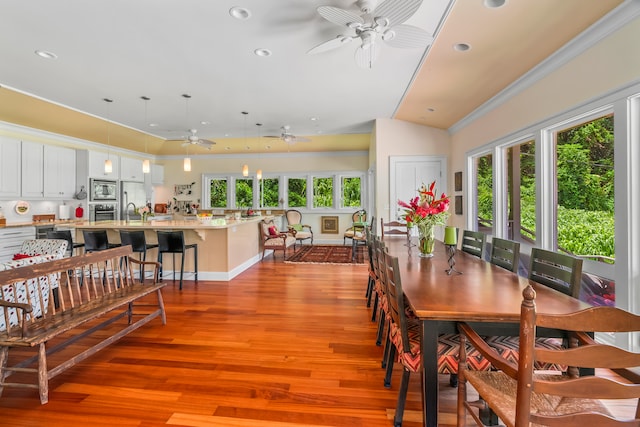 dining area with ceiling fan, hardwood / wood-style flooring, ornamental molding, and a healthy amount of sunlight