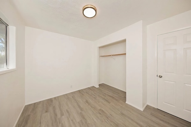 unfurnished bedroom featuring a closet, light hardwood / wood-style floors, and a textured ceiling