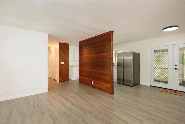 unfurnished room featuring a textured ceiling, light hardwood / wood-style flooring, and french doors