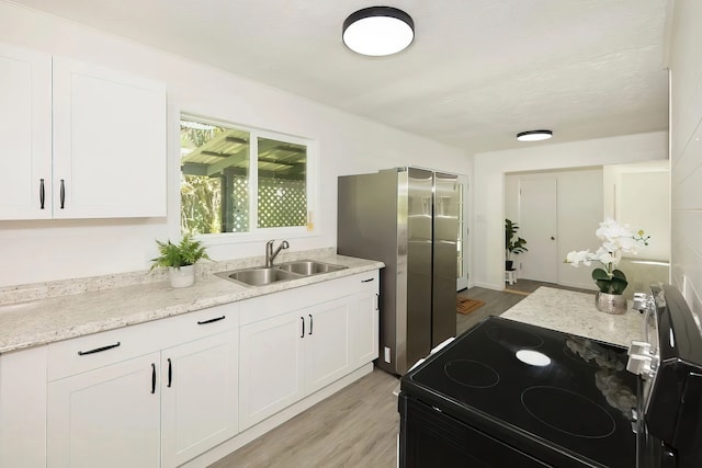 kitchen with light wood-type flooring, stainless steel electric range, white cabinets, and sink