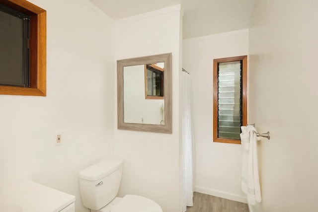 bathroom featuring toilet, ornamental molding, and wood-type flooring