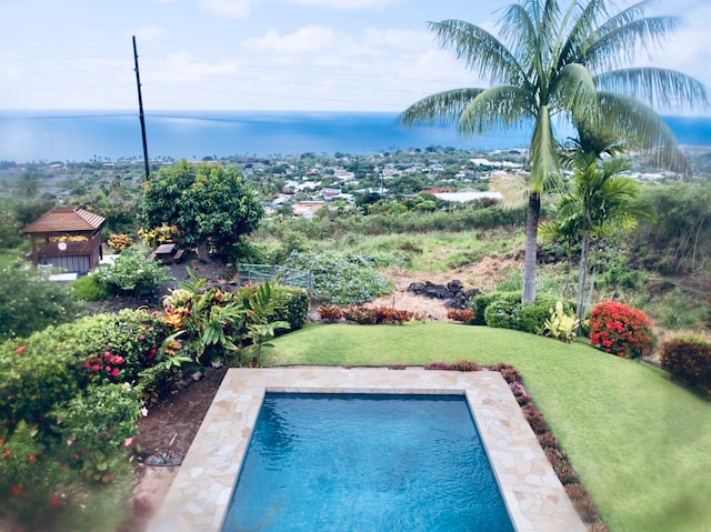 view of swimming pool featuring a yard and a water view