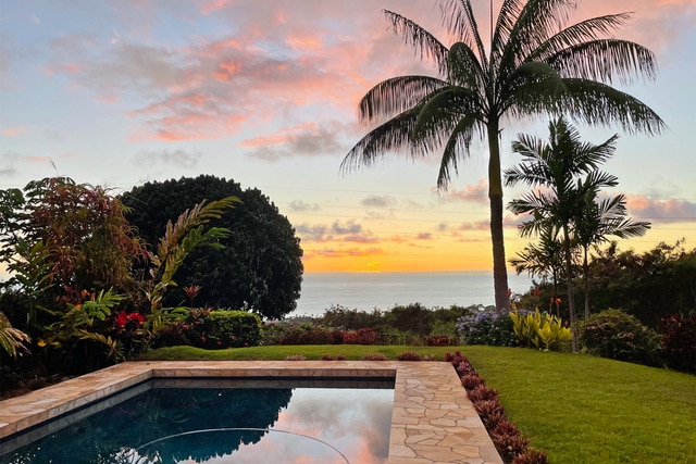 pool at dusk featuring a water view and a yard