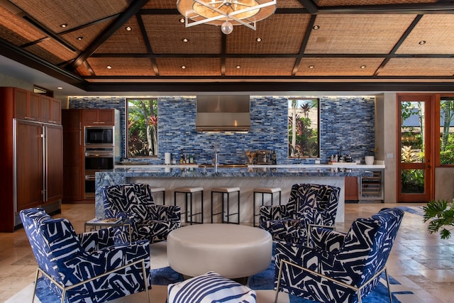 interior space featuring backsplash, wood ceiling, appliances with stainless steel finishes, wall chimney exhaust hood, and beverage cooler