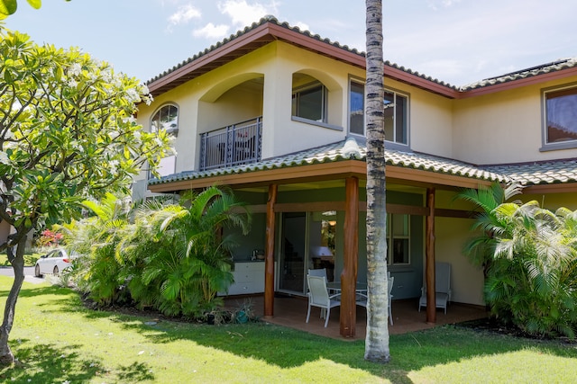 back of property with a yard and a balcony