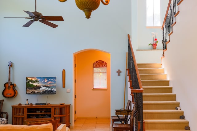 stairway with plenty of natural light, a high ceiling, and tile patterned floors