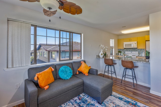 living room with dark wood-type flooring, ceiling fan, and a healthy amount of sunlight