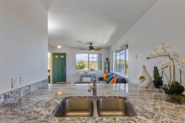 kitchen with ceiling fan, sink, and light stone countertops