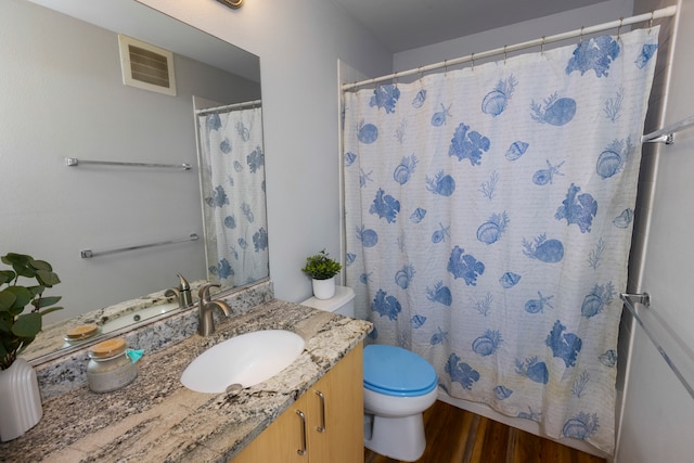 bathroom with hardwood / wood-style floors, walk in shower, toilet, and vanity