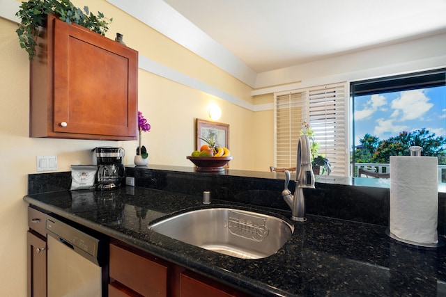 kitchen with dark stone counters, dishwashing machine, and sink