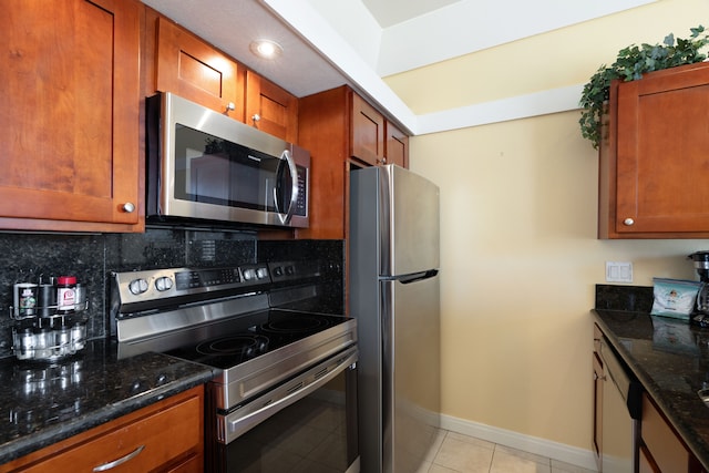 kitchen with dark stone countertops, backsplash, stainless steel appliances, and light tile patterned flooring