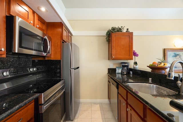 kitchen featuring light tile patterned floors, tasteful backsplash, stainless steel appliances, sink, and dark stone countertops