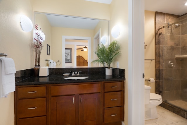 bathroom featuring tiled shower, vanity, toilet, and tile patterned flooring