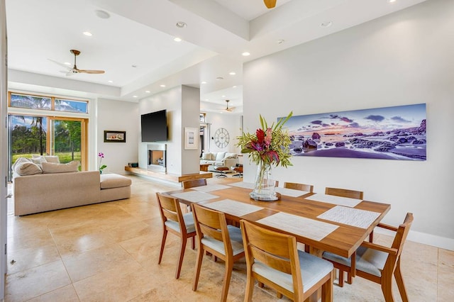 dining area featuring a tray ceiling, light tile patterned floors, and ceiling fan