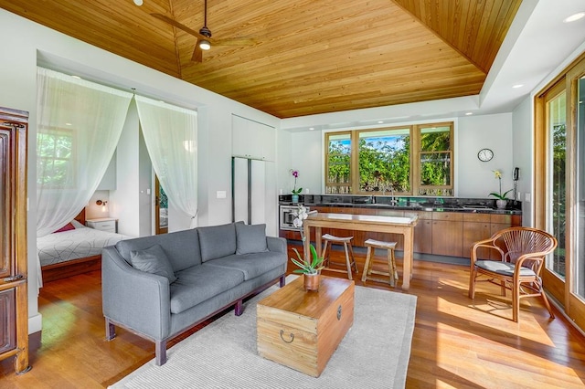 living room featuring sink, a tray ceiling, wooden ceiling, and light hardwood / wood-style flooring