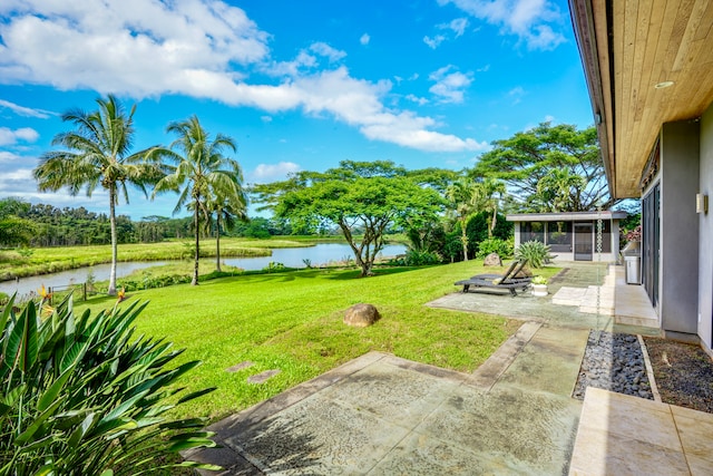 view of yard with a sunroom, a water view, and a patio area