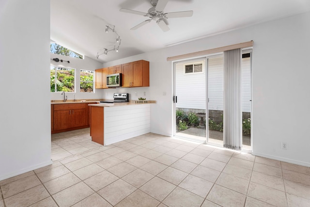 kitchen featuring kitchen peninsula, light tile patterned floors, vaulted ceiling, sink, and stainless steel appliances