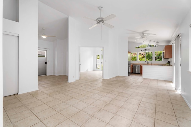 unfurnished living room featuring sink, high vaulted ceiling, and light tile patterned floors