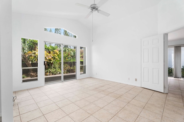 empty room with high vaulted ceiling, light tile patterned floors, and ceiling fan