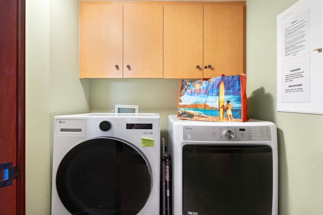 clothes washing area featuring cabinets and washer and clothes dryer