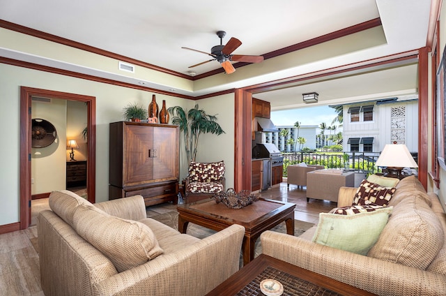living room with ornamental molding, visible vents, ceiling fan, and baseboards