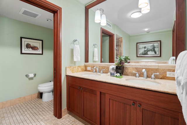 bathroom with toilet, double vanity, a sink, and visible vents