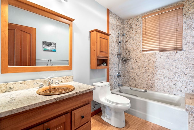 full bathroom featuring tiled shower / bath, toilet, hardwood / wood-style flooring, and vanity