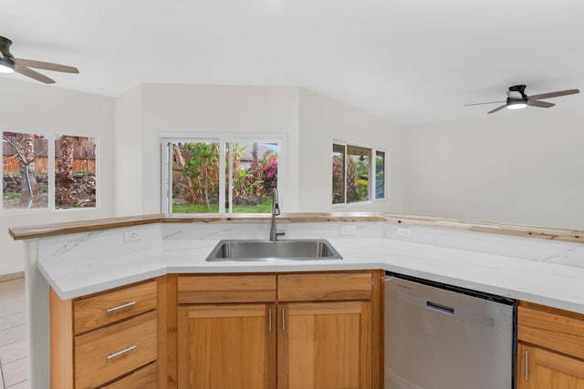 kitchen with a sink, light stone countertops, ceiling fan, and stainless steel dishwasher