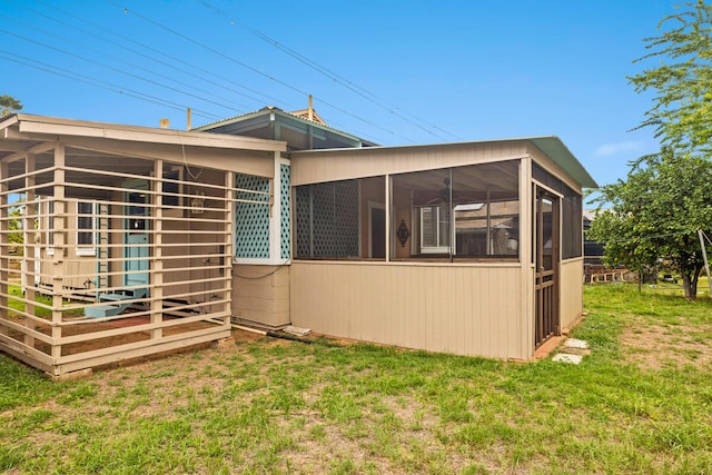 back of property featuring a lawn and a sunroom