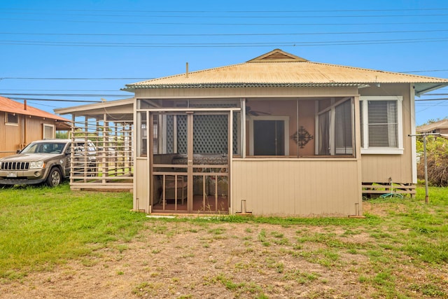 rear view of house featuring a sunroom and a lawn