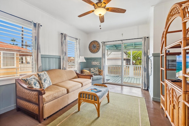 living room featuring ceiling fan, ornamental molding, and dark wood-type flooring