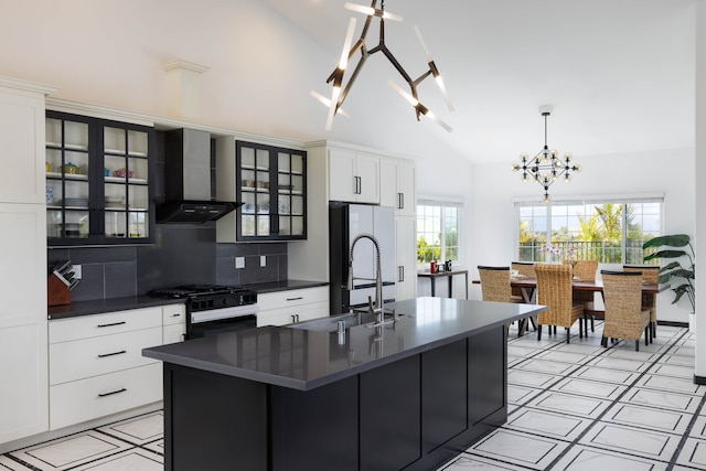 kitchen with a kitchen island with sink, a chandelier, range with gas stovetop, wall chimney exhaust hood, and lofted ceiling