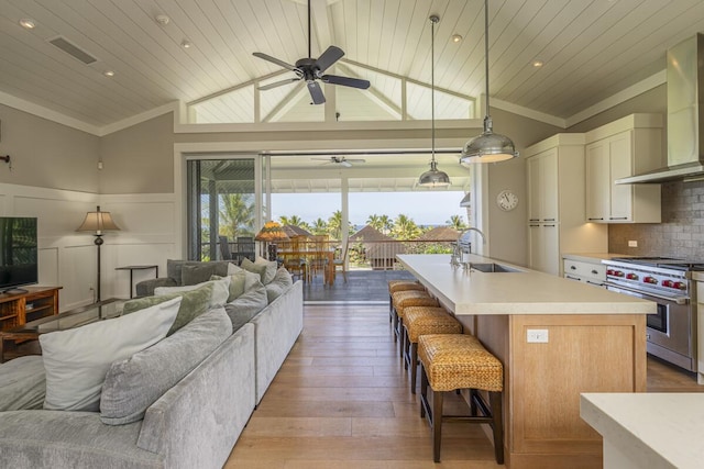 kitchen with premium range, ornamental molding, sink, ceiling fan, and wall chimney exhaust hood