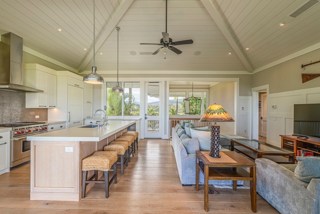 kitchen featuring wall chimney exhaust hood, luxury stove, sink, and light hardwood / wood-style floors