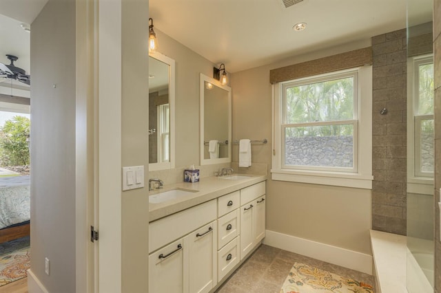 bathroom with double vanity, ensuite bath, a sink, and baseboards