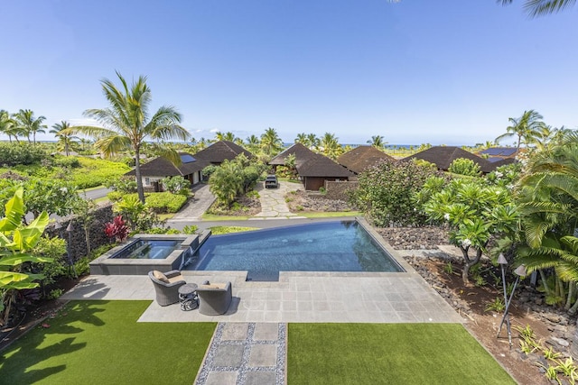 outdoor pool featuring a yard, an in ground hot tub, and a patio