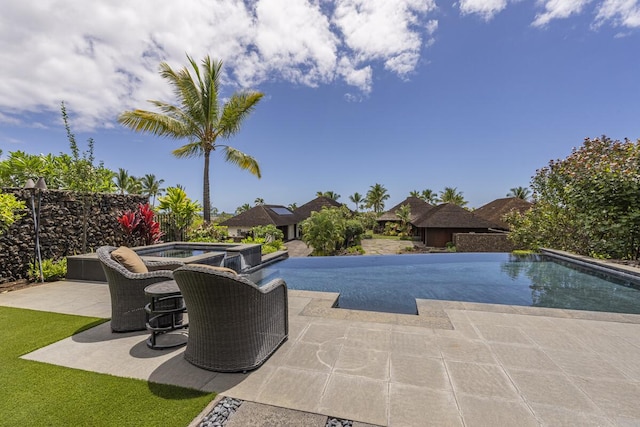 pool with an in ground hot tub, a patio area, and fence