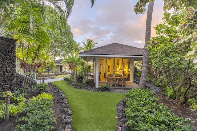 back house at dusk with a lawn