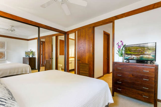 bedroom with ceiling fan, light colored carpet, crown molding, and ensuite bath